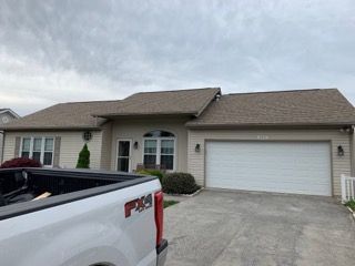 Beige house with a brown roof and white garage door; a white truck is in the foreground.