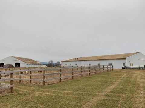 Farm buildings and a fence on a cloudy day.
