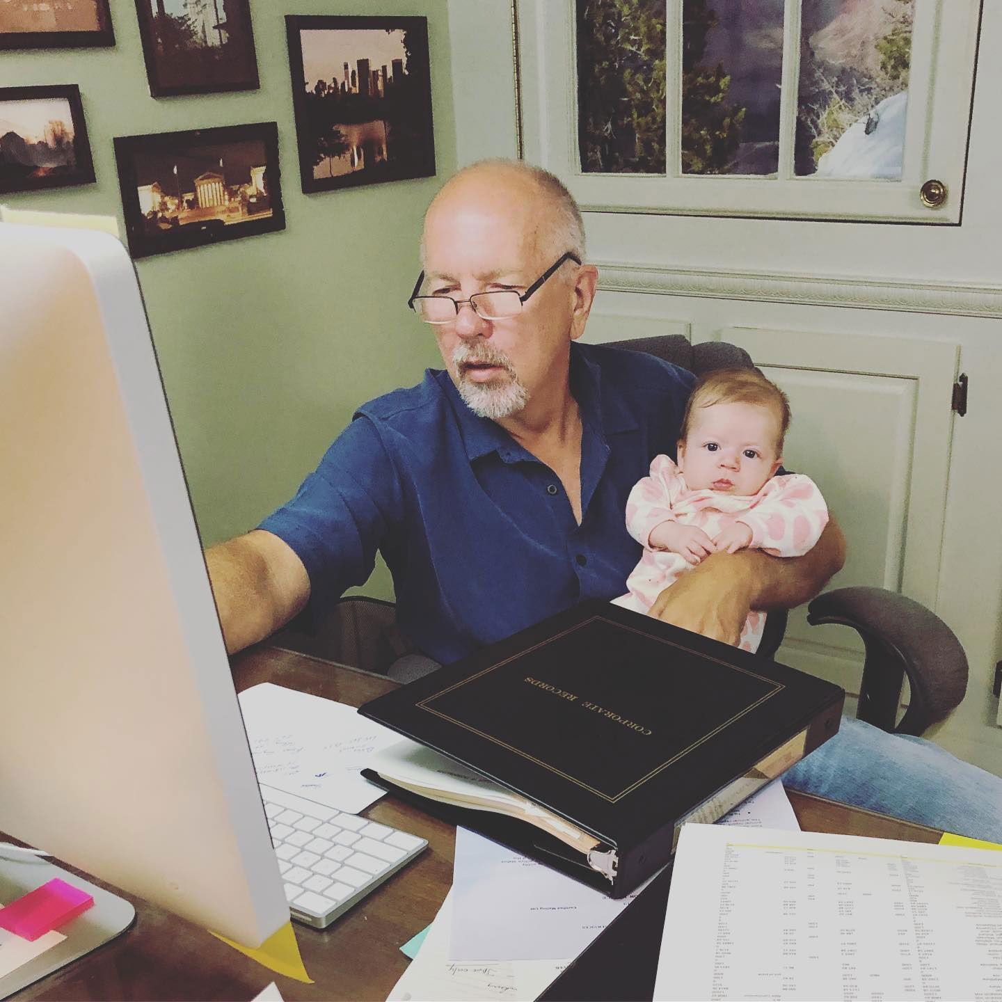 A man is holding a baby while using a computer