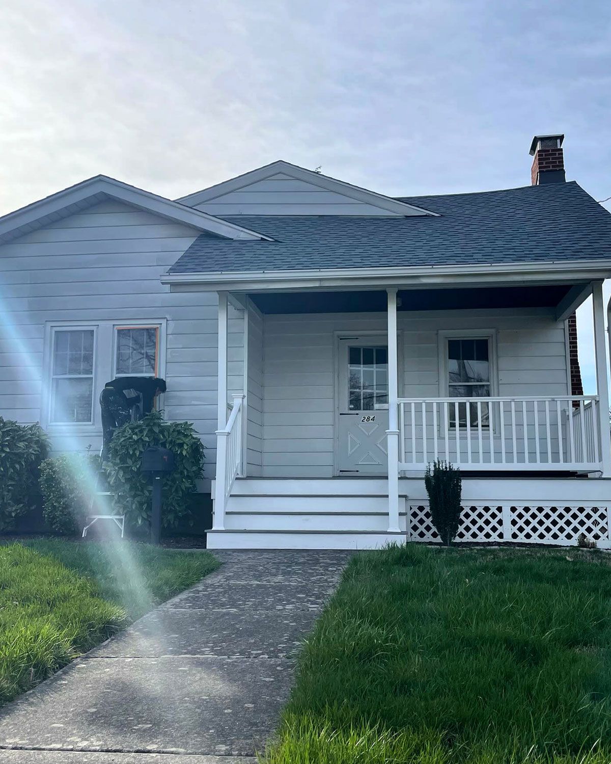 A white house with a porch and a gray roof.