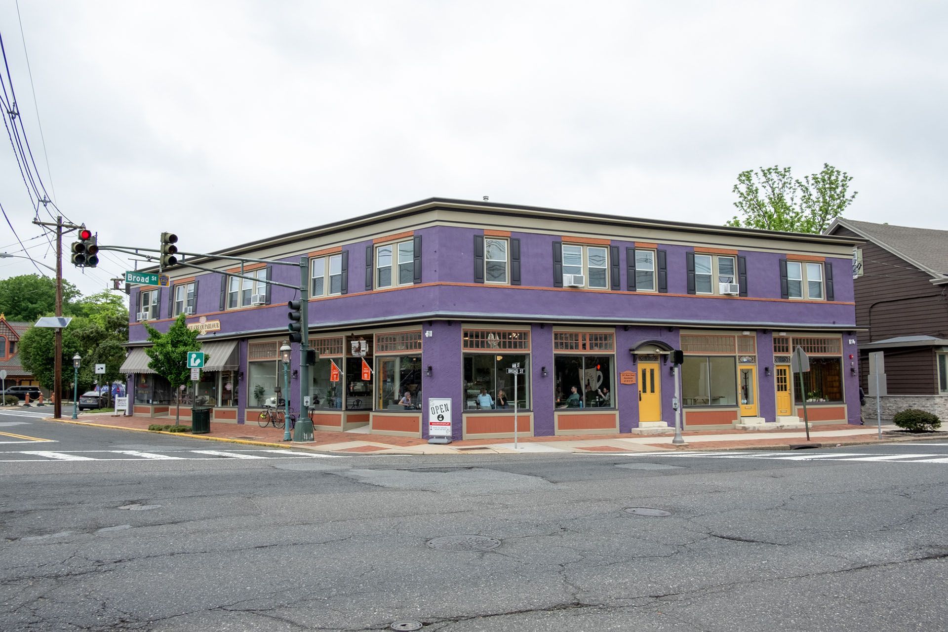 A purple building with a yellow door is on the corner of a street.