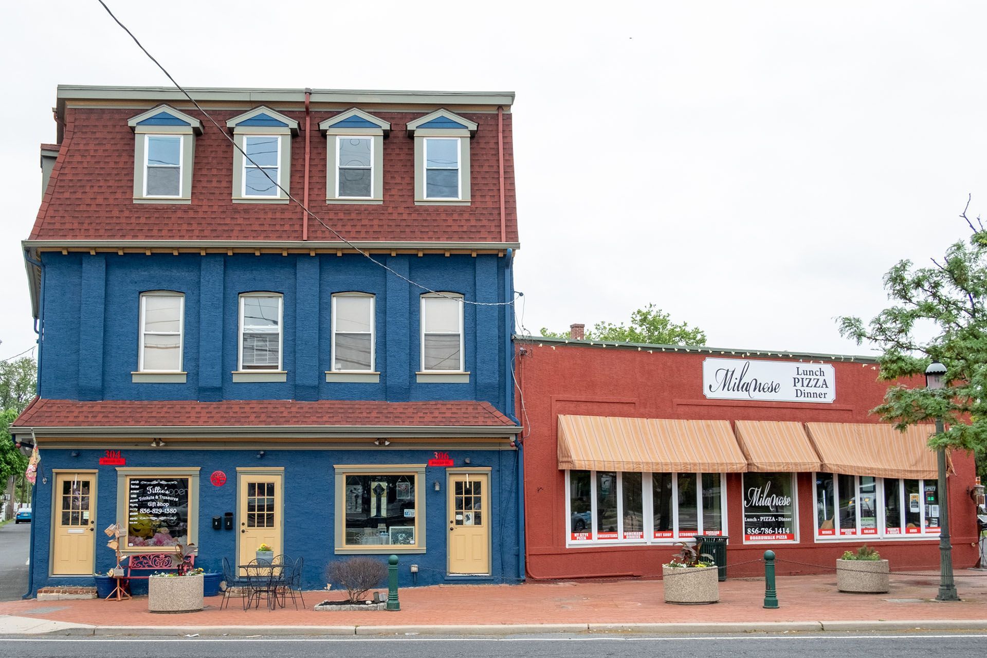 A blue building with a red roof is next to a red building