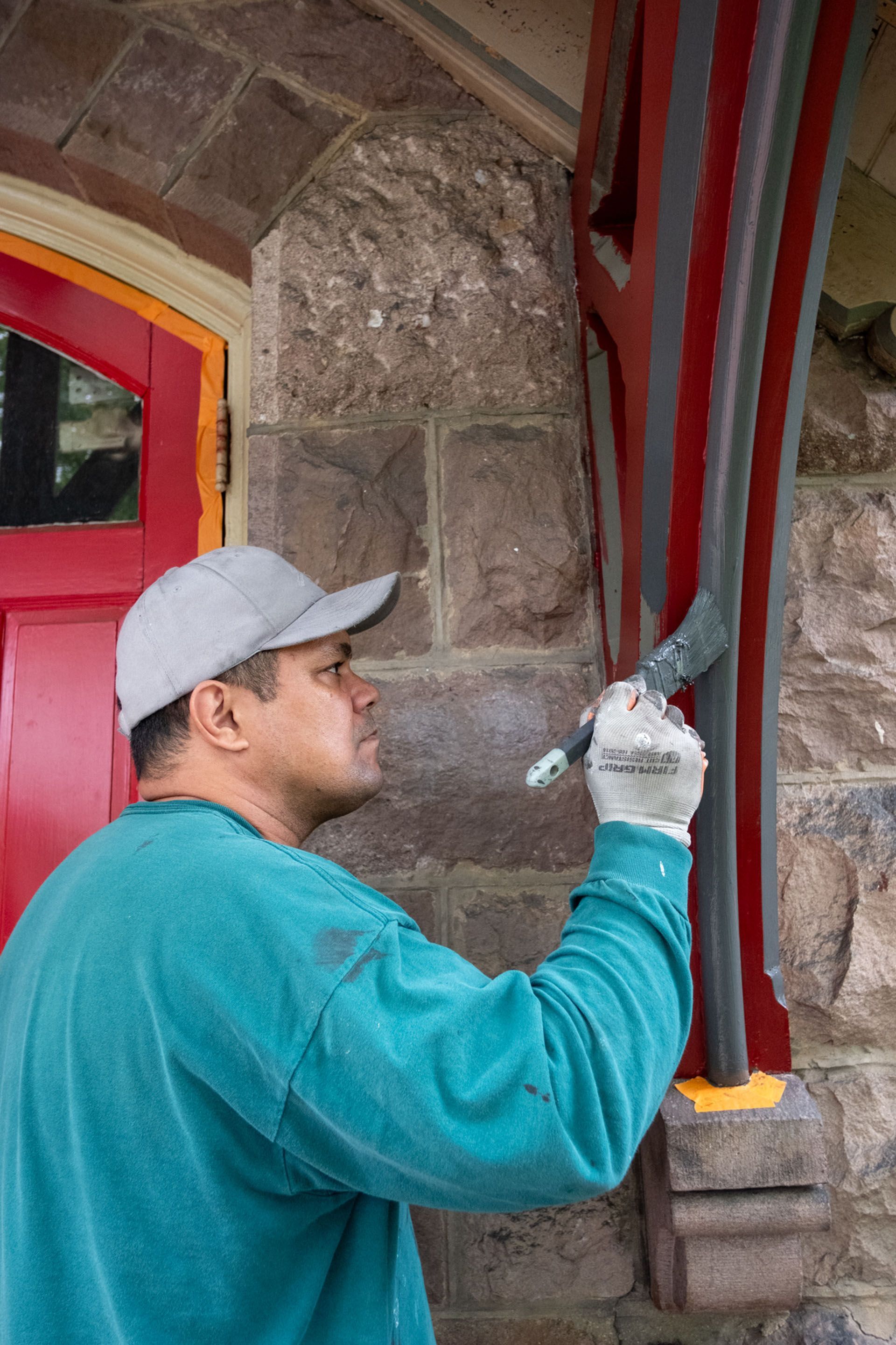 A man is painting a stone wall with a brush.