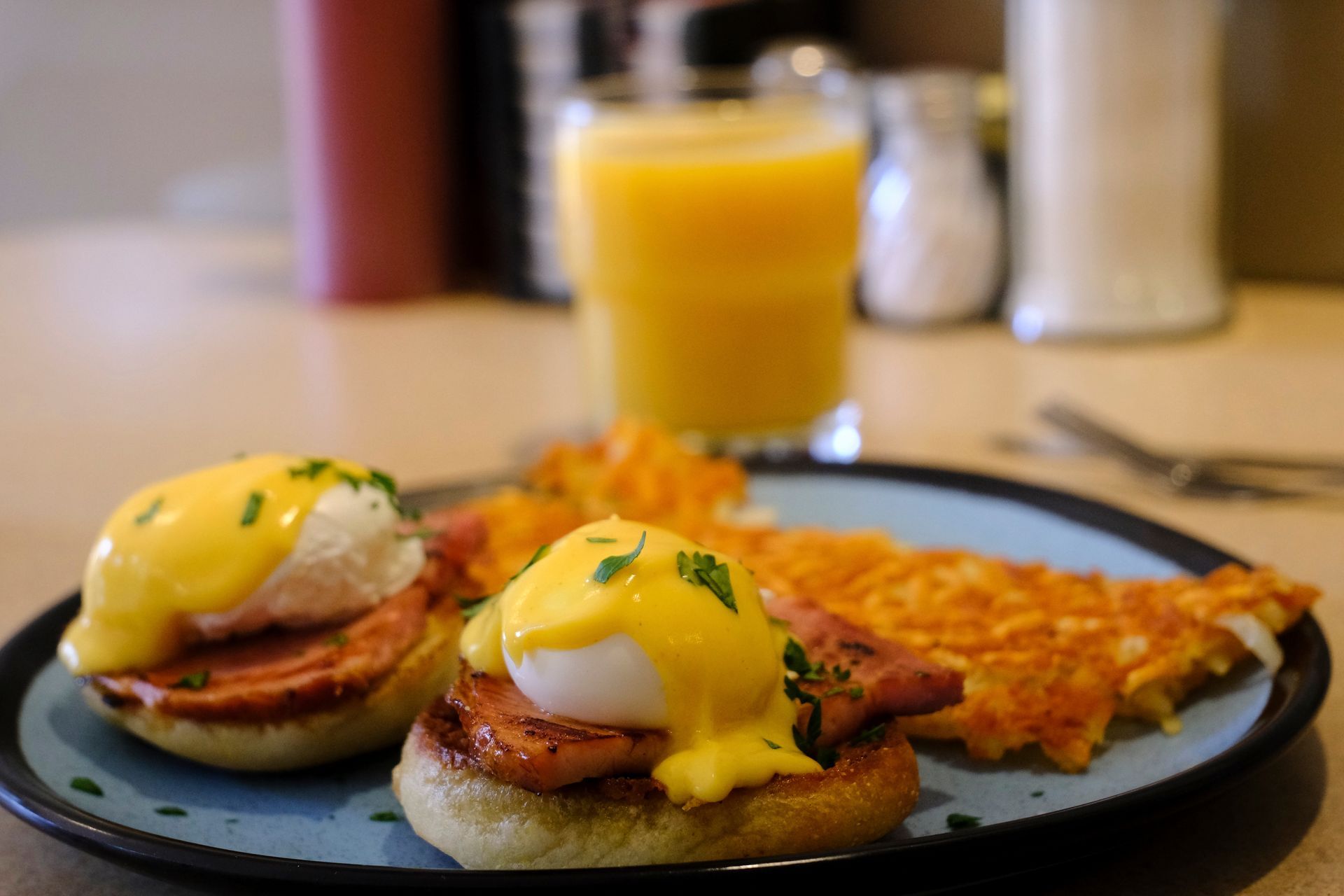 Eggs Benedict with hash browns and orange juice.