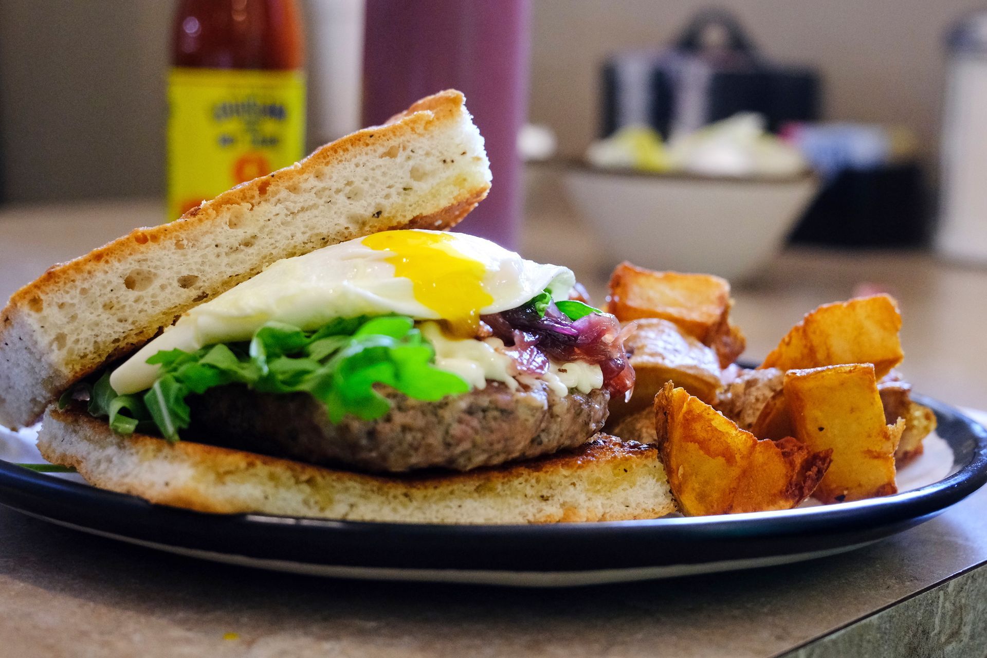 Burger with fried egg and arugula, served with potato wedges.