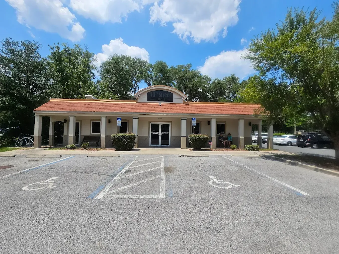 A one-story building with a red-tiled roof and accessible parking spaces, sunny day.