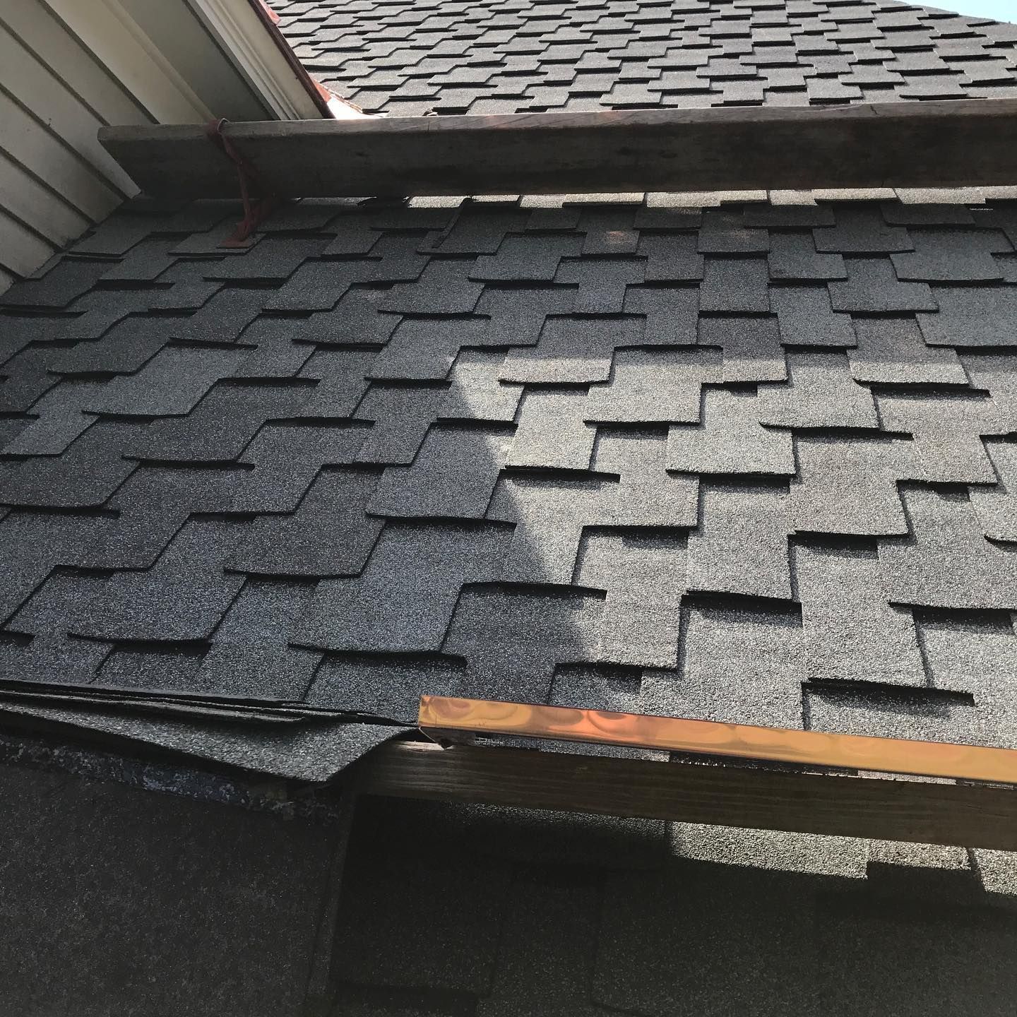 Gray shingle roof, partially covered by a wooden beam; bright daylight.