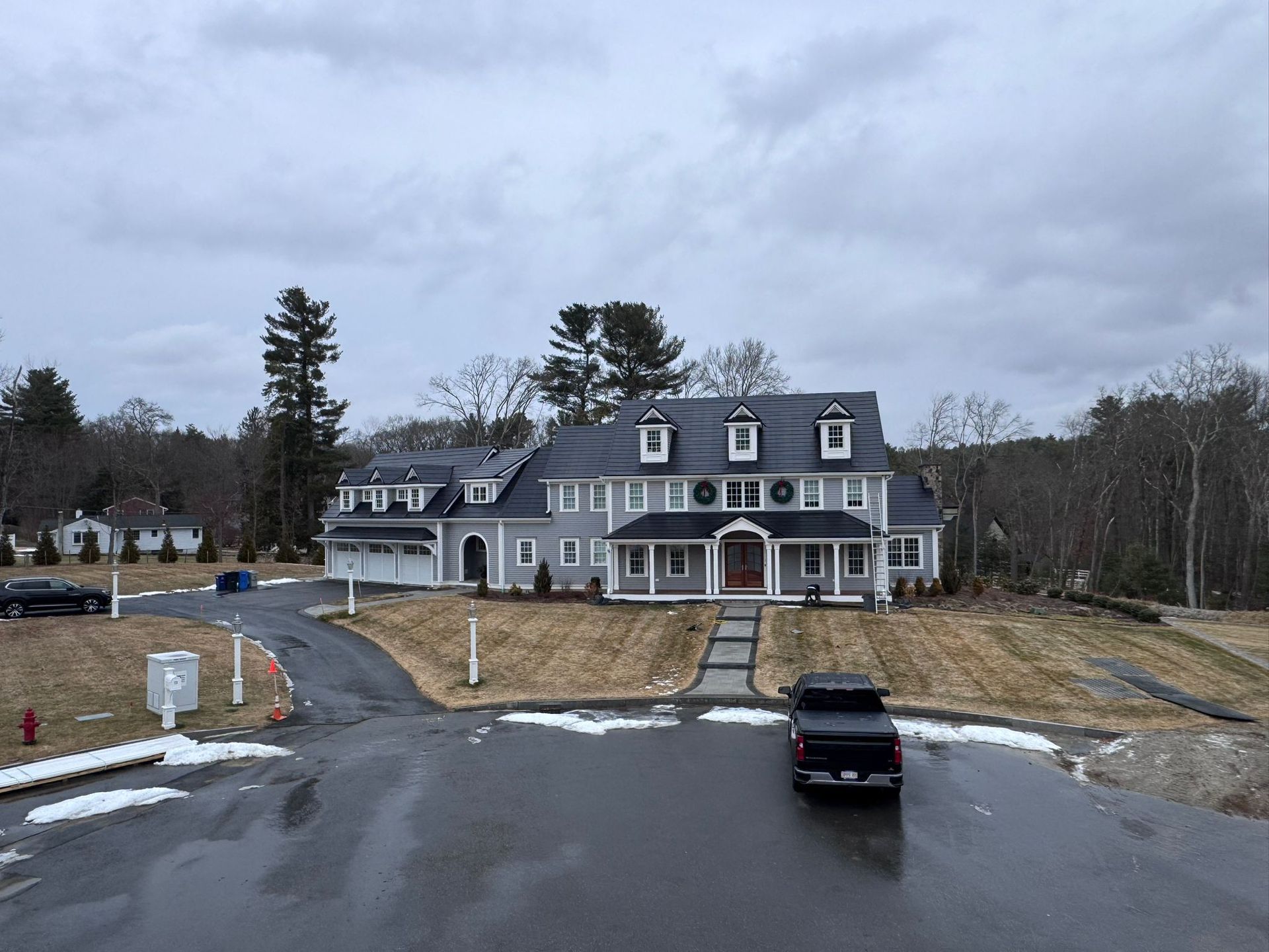 Large gray house with a black pickup truck parked in front on a cloudy day.