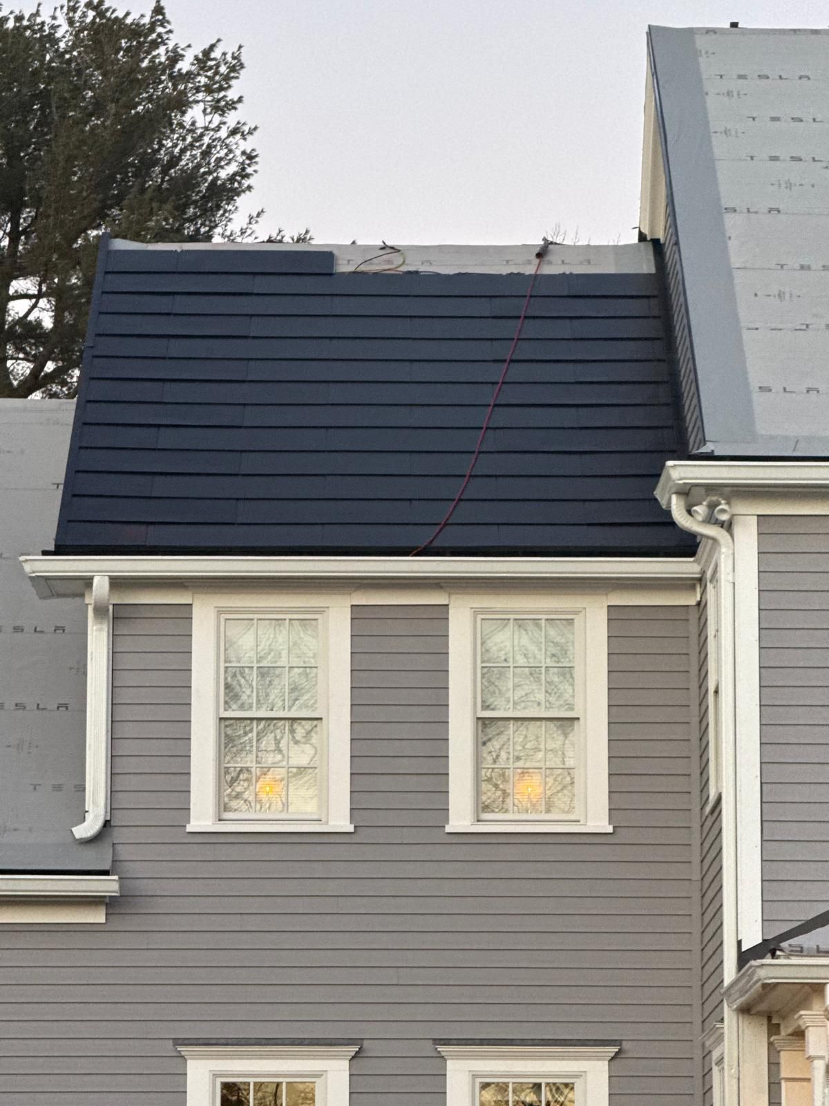 Gray house with two windows and a dark blue roof.