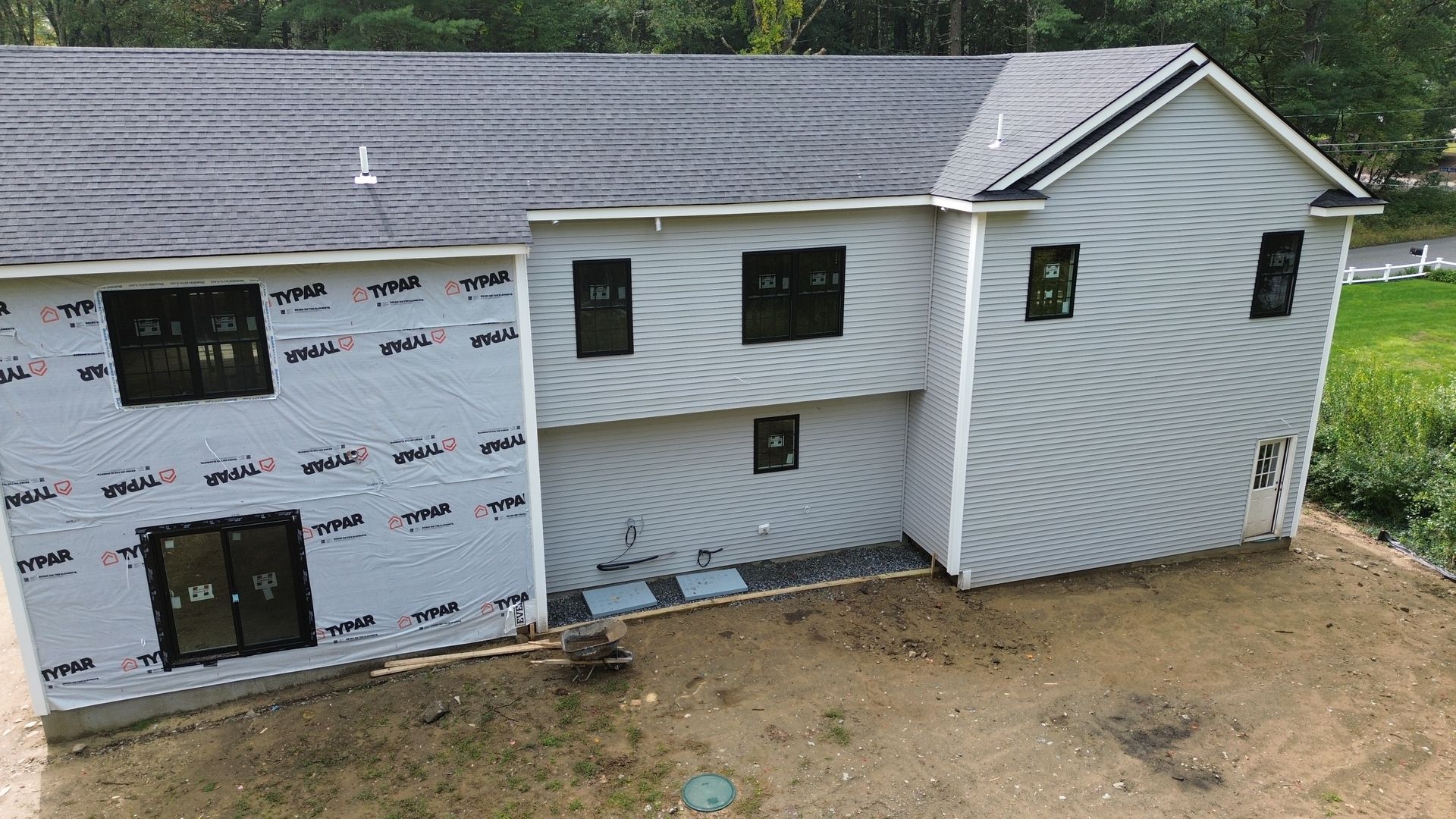 Newly constructed house with gray siding, dark windows, and a dark roof.