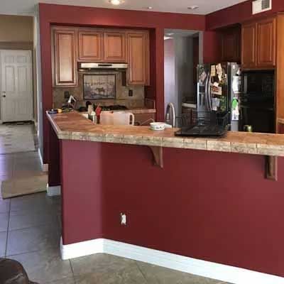 Kitchen with burgundy walls, brown cabinets, and a bar with a tile countertop.