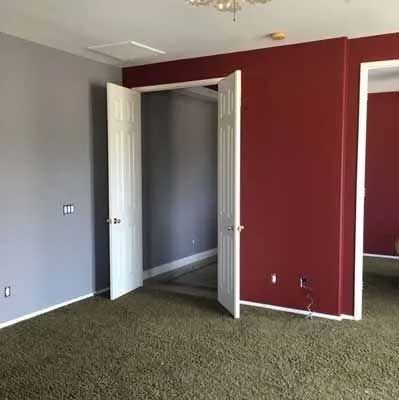 Room with gray and red walls, white doors and trim, green carpet.