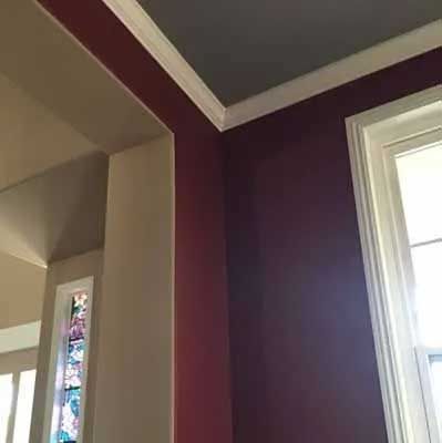 Corner of a room with plum walls, white trim, and a window; the ceiling is gray.