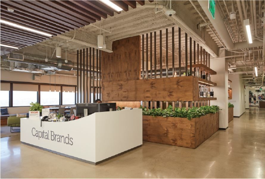 A large room with a white counter that says capital brands on it.