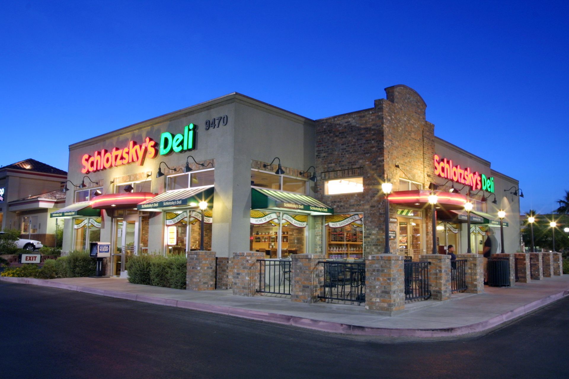 A deli is located on the corner of a street at night.