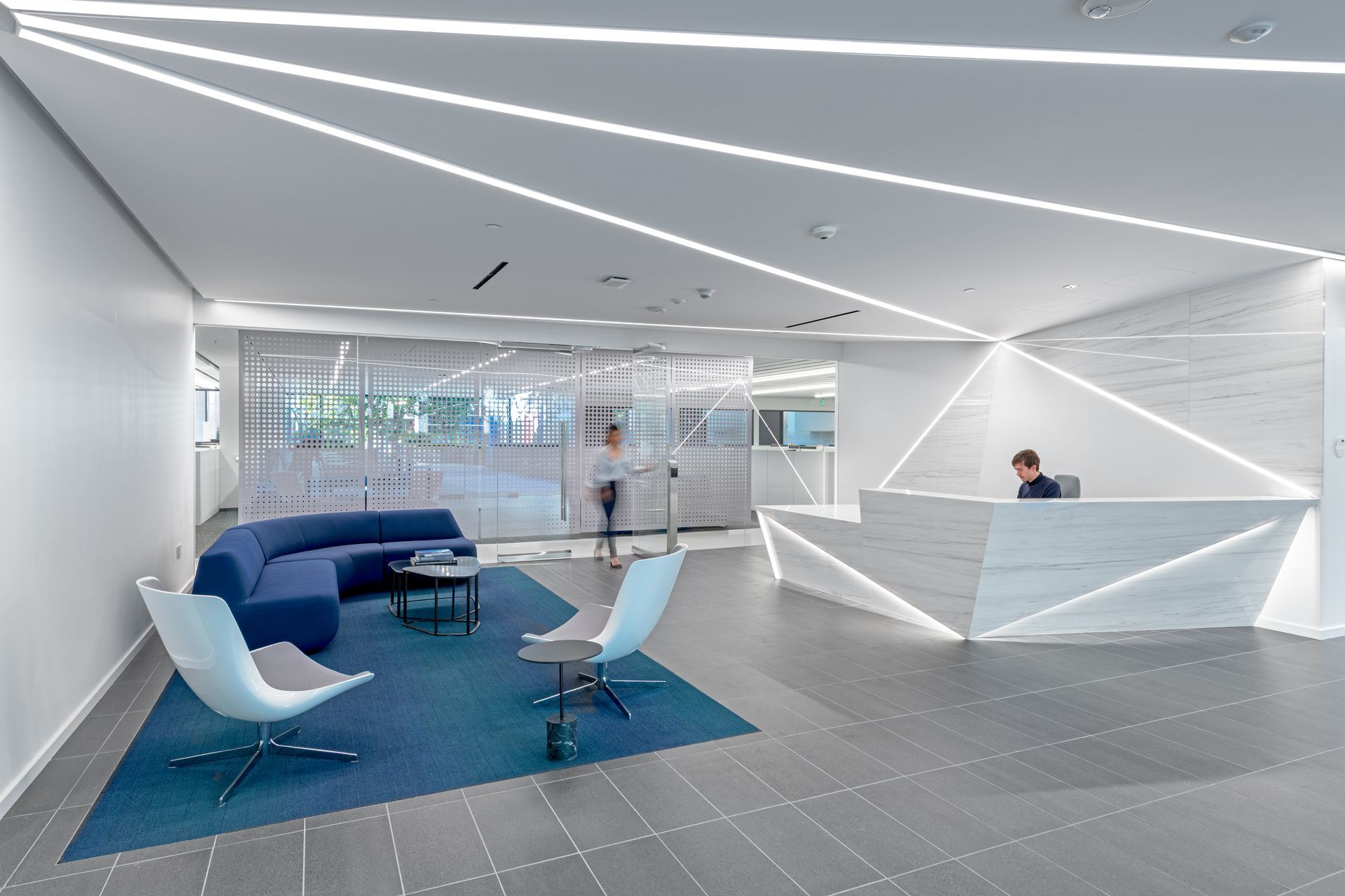 A lobby with a couch , chairs , and a reception desk.