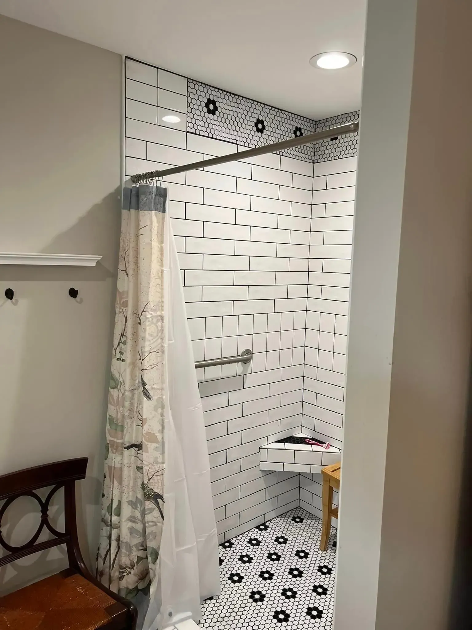 A bathroom with a shower curtain and a bench.