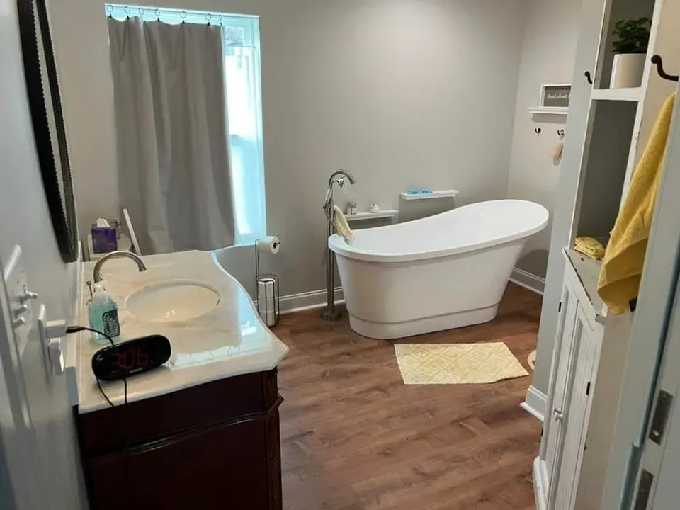 A bathroom with a tub , sink and mirror.