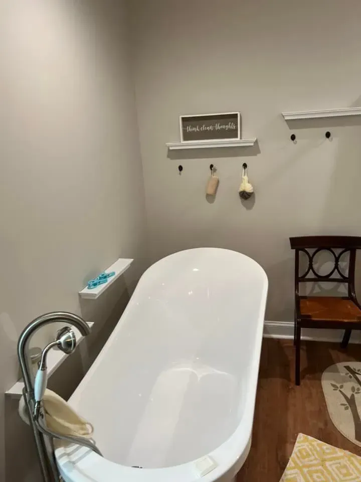 A bathroom with a claw foot tub and a chair.
