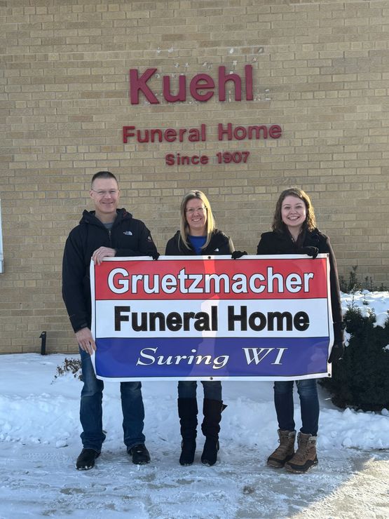 A group of people holding a sign in front of a funeral home.