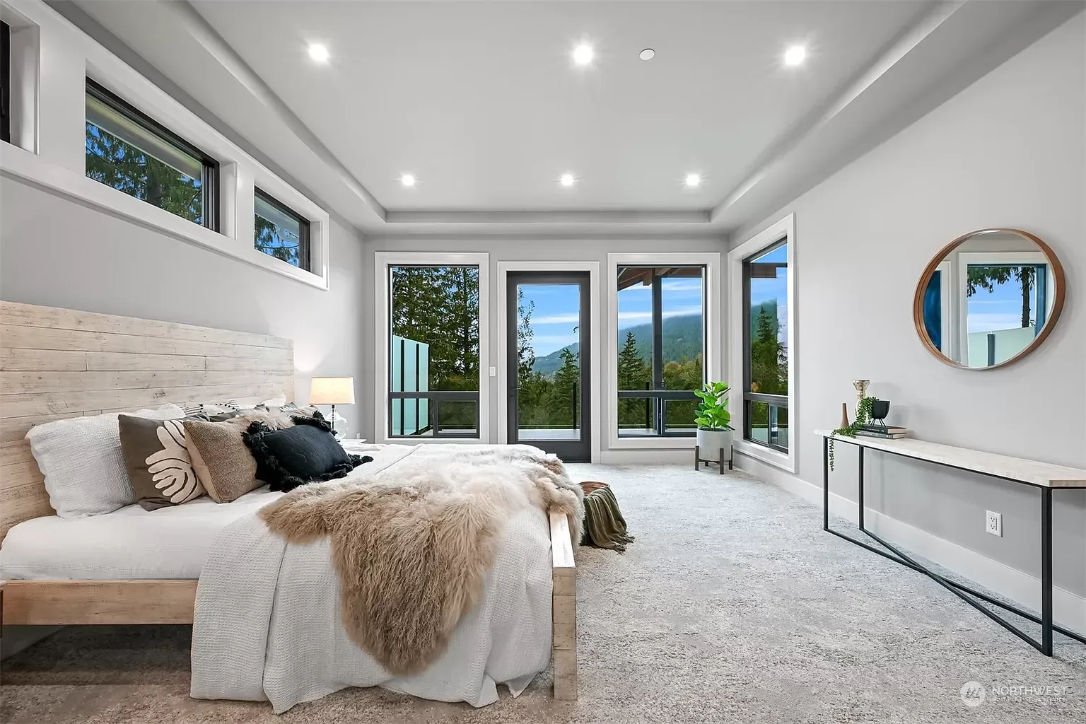 A bedroom with two beds , a mirror and a lot of windows.