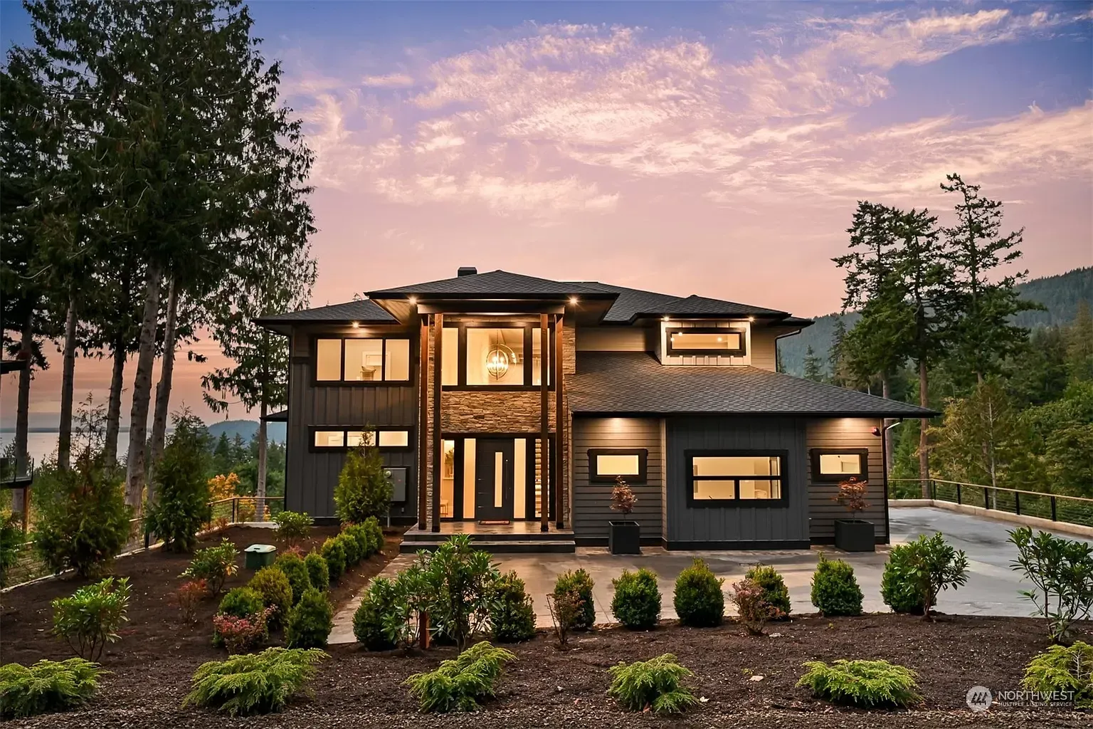 A large house with a lot of windows is surrounded by trees and bushes.