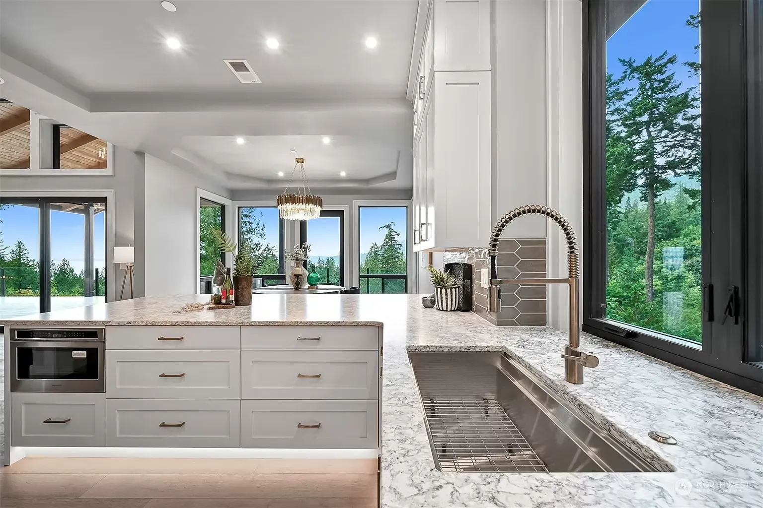 A kitchen with white cabinets , granite countertops , a sink , and a large window.