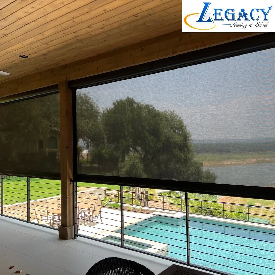 Backyard patio with black screens, concrete flooring, and a grassy lawn under a cloudy sky.