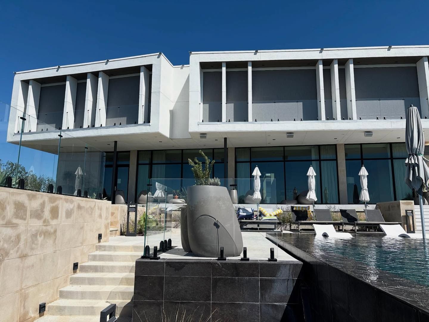 Modern white house with glass windows and a pool.