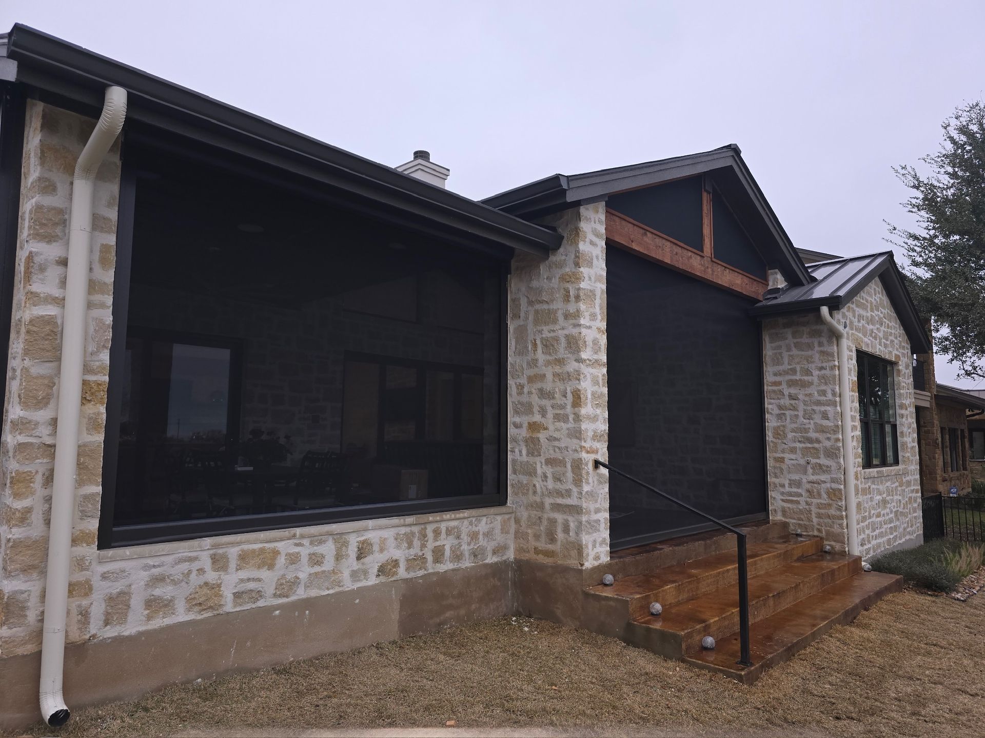House exterior with stone facade, dark window shades, and a covered porch.