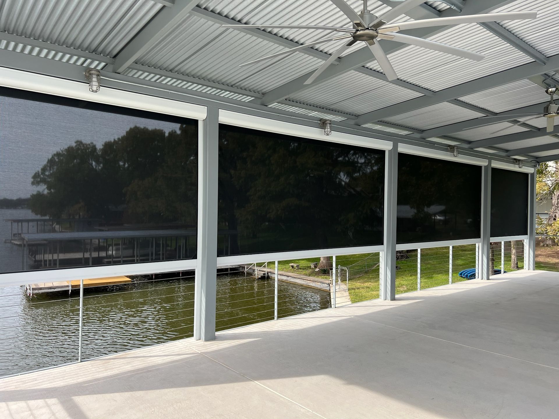 Patio with retractable black sun shades, overlooking a lake and dock.