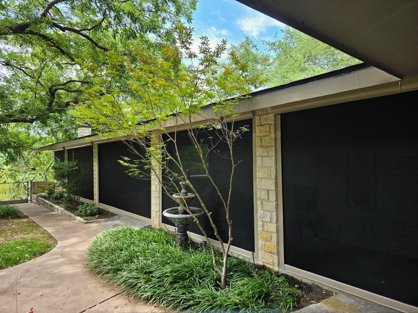 Exterior of a home with black solar screens. A walkway and landscaping are in front.