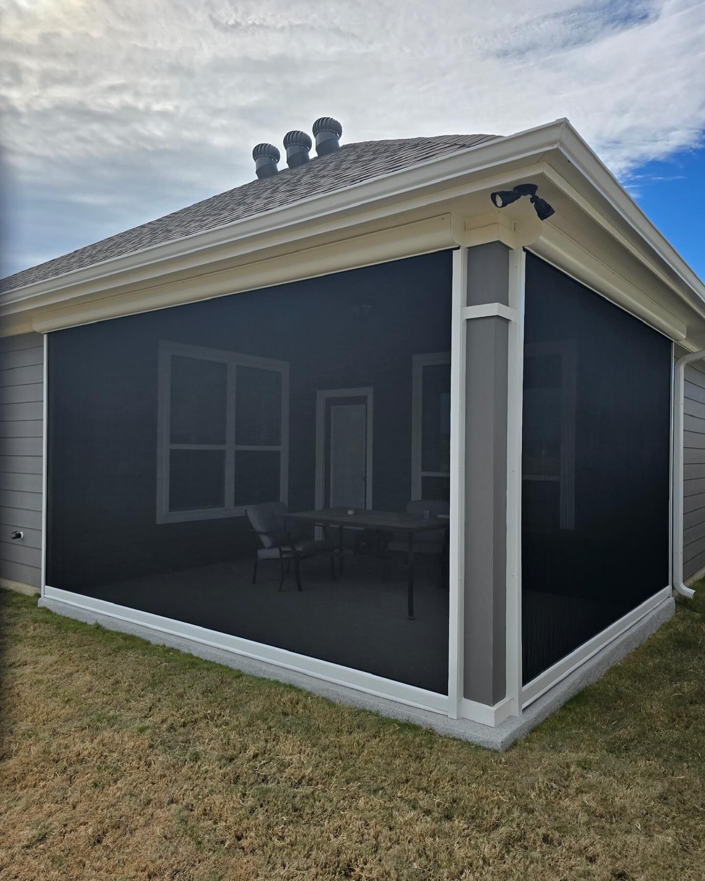 Screened-in porch with black screen walls, white trim, and a view of a table and chairs inside.