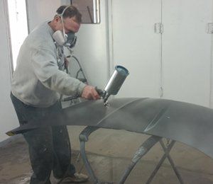 Technician repainting a  car hood