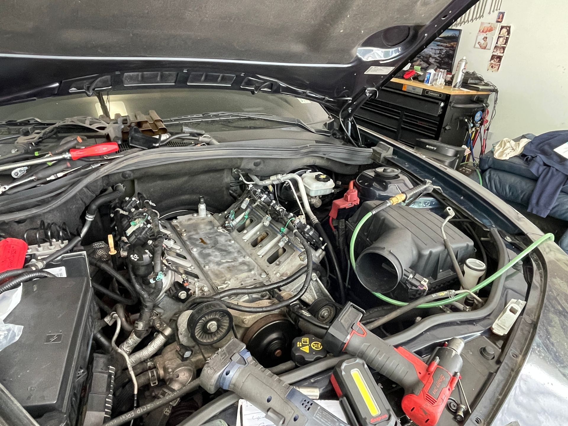 Open car engine bay with exposed V8 and loose tools, showing maintenance in progress