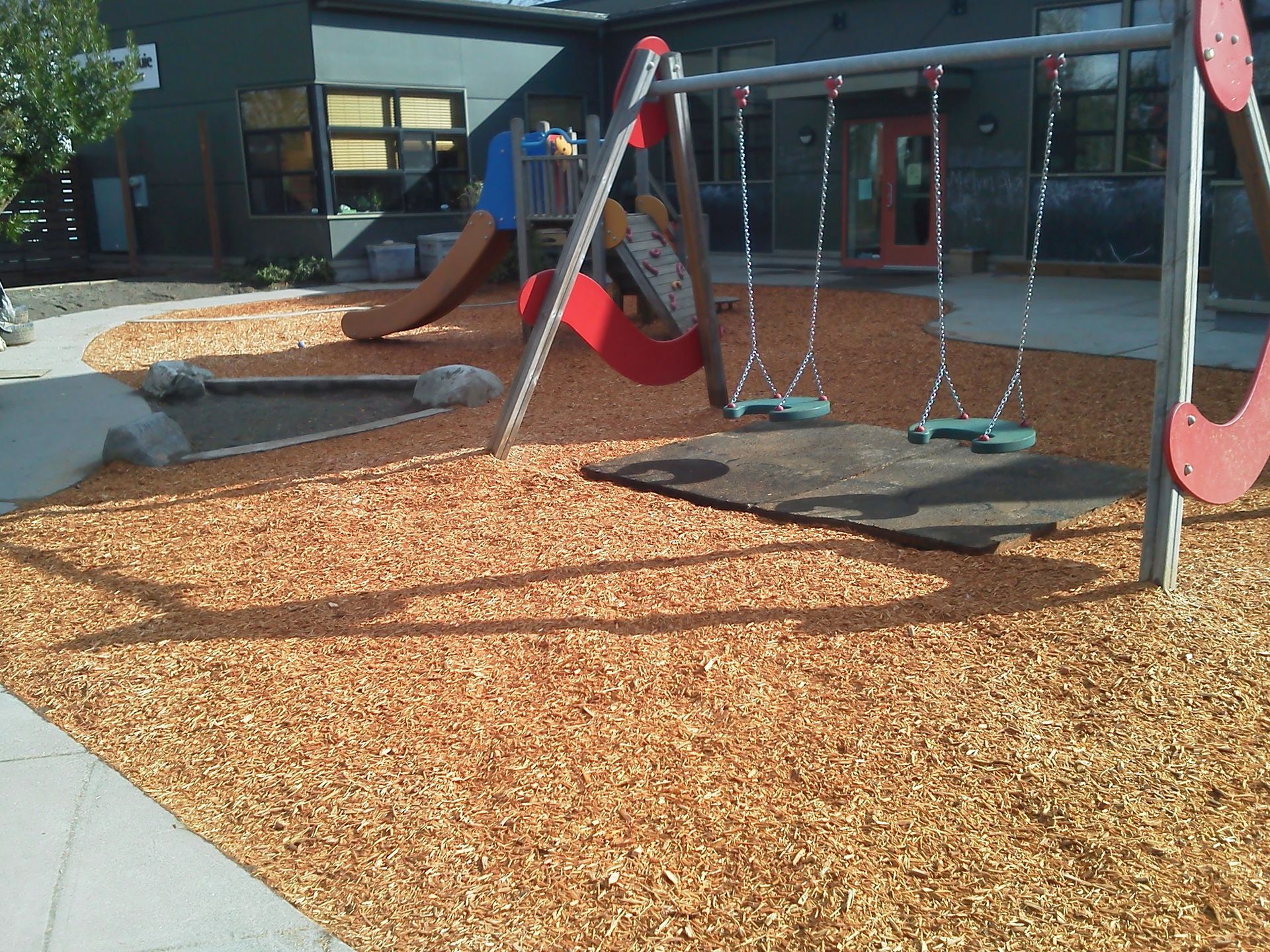 a playground with swings and a slide in front of a building