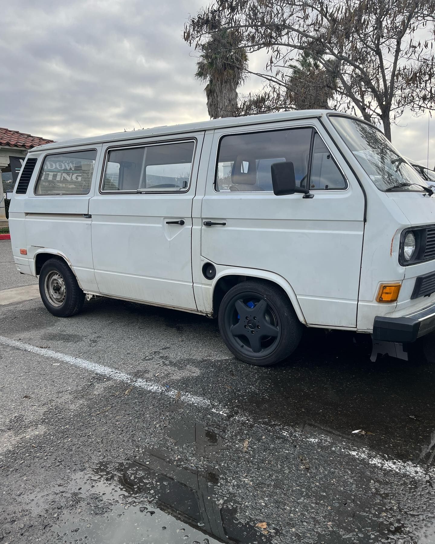 White Volkswagen Van parked on asphalt, cloudy sky overhead.