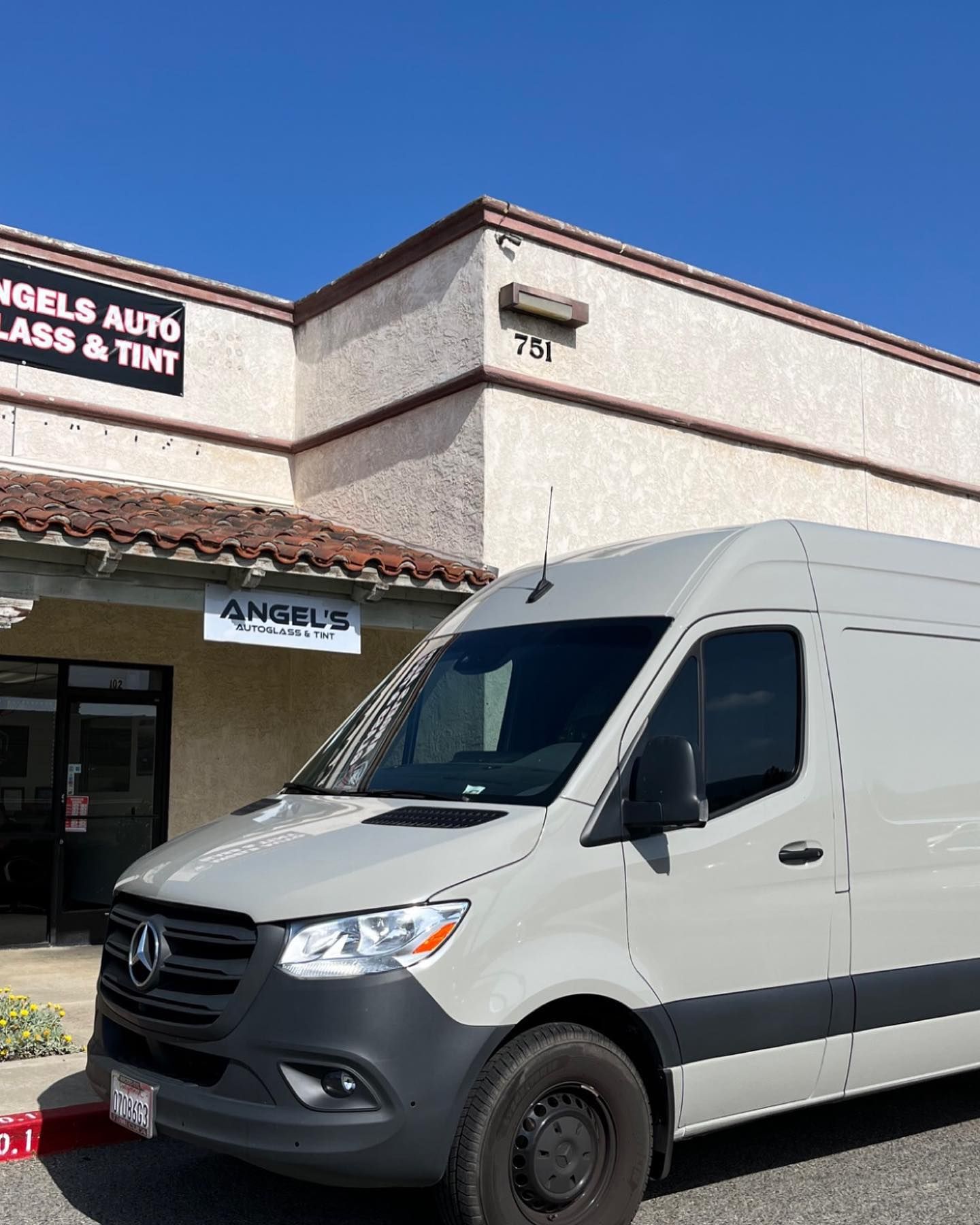 A gray Mercedes-Benz van parked in front of Angels Auto Glass & Tint storefront.