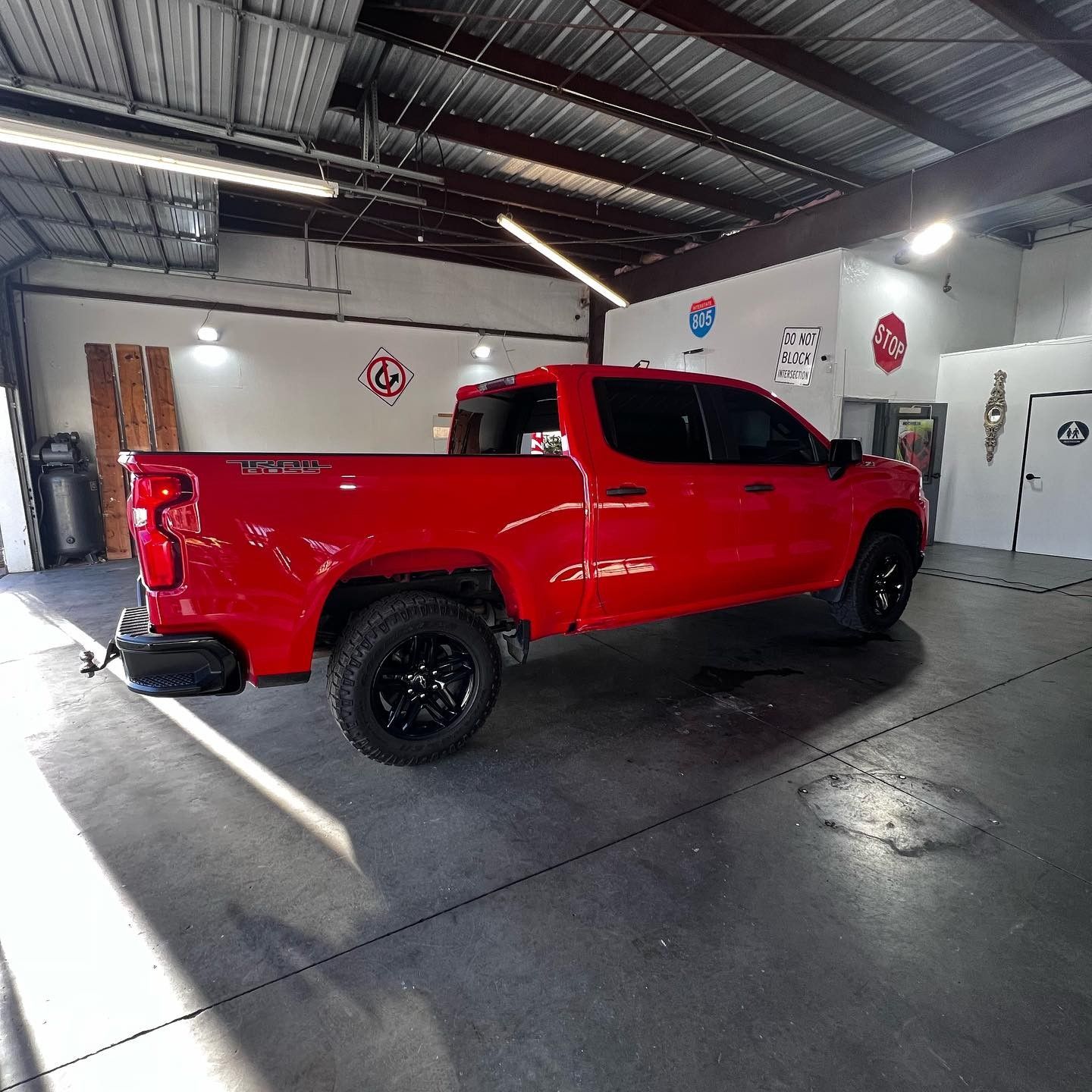 Bright red pickup truck in a garage with black wheels and a black bumper.