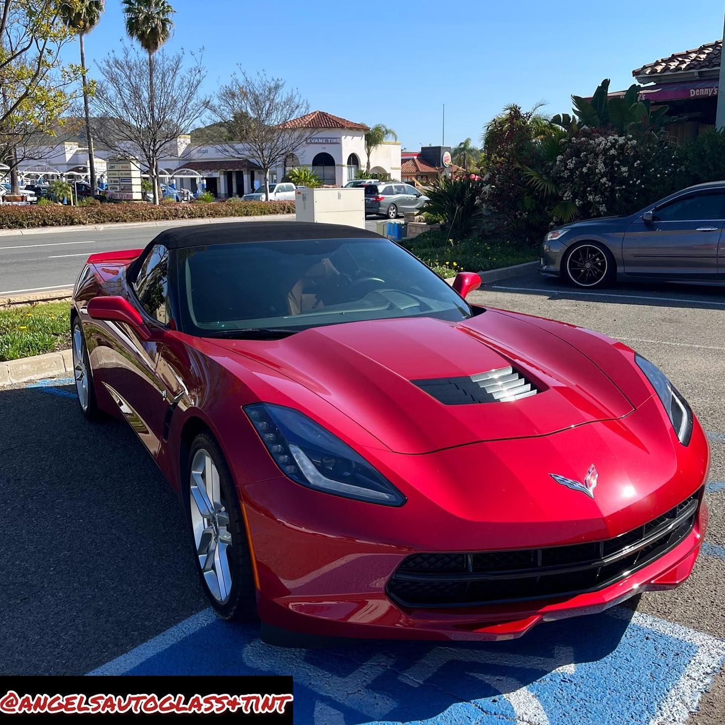 Red Corvette convertible parked on a sunny day in front of a building.
