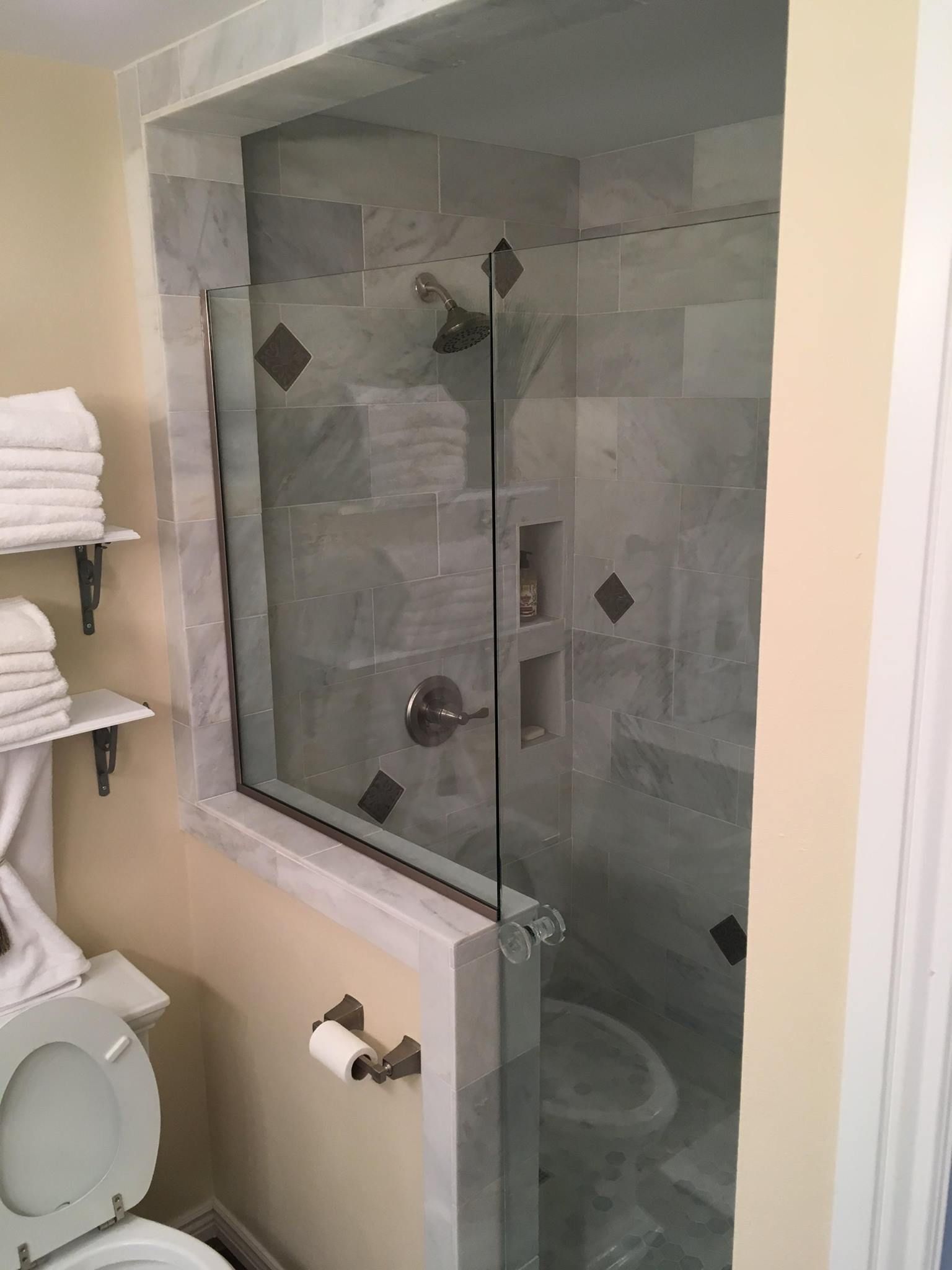 A bathroom with a toilet , shower , and window.