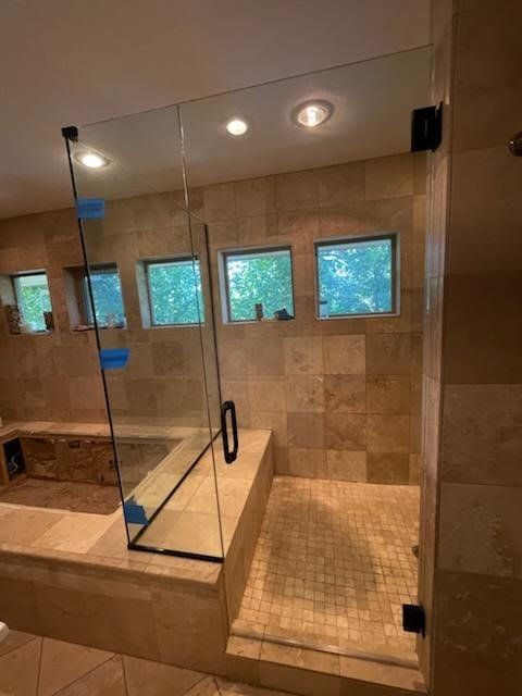 A bathroom with a walk in shower with a glass door
