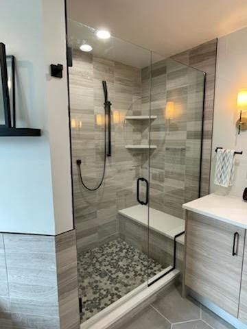 A bathroom with a walk in shower and a sink.