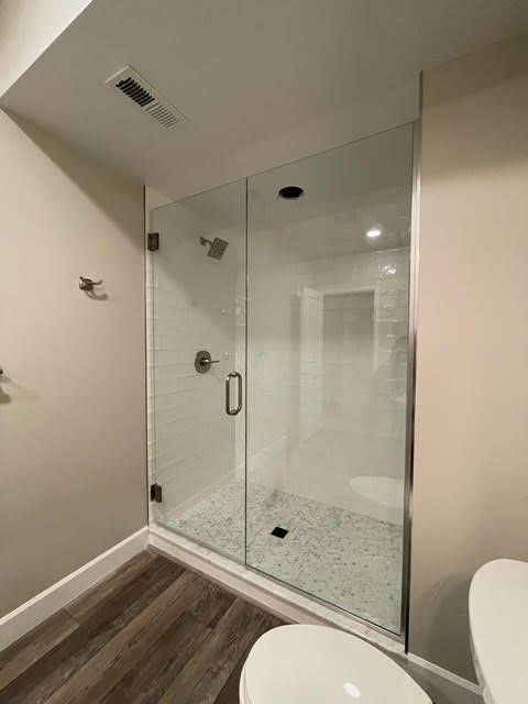 A bathroom with a walk in shower and a toilet.