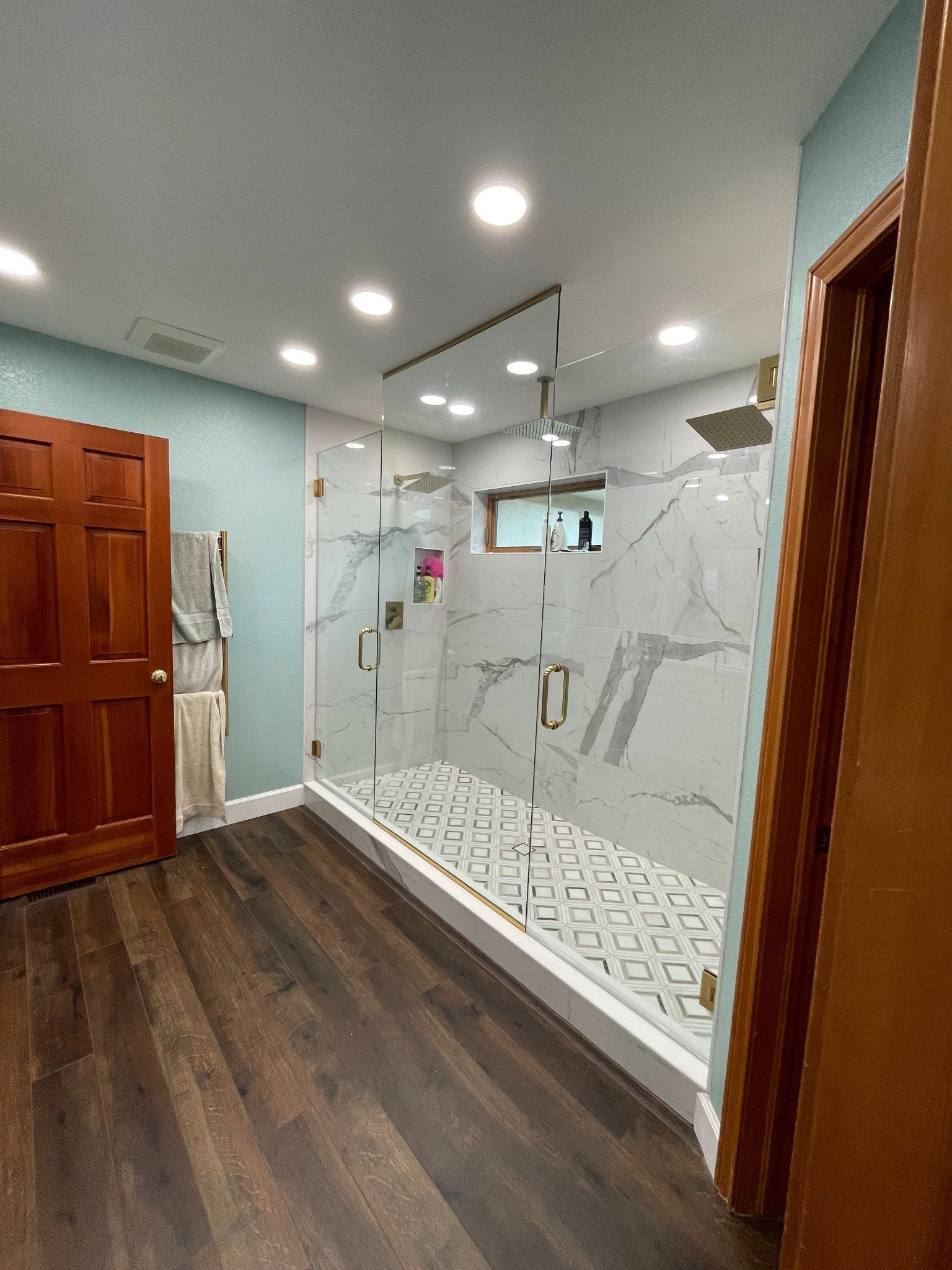 A bathroom with a walk in shower and a wooden floor.