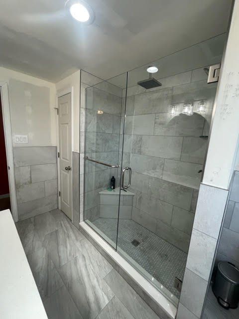 A bathroom with a walk in shower with a glass door
