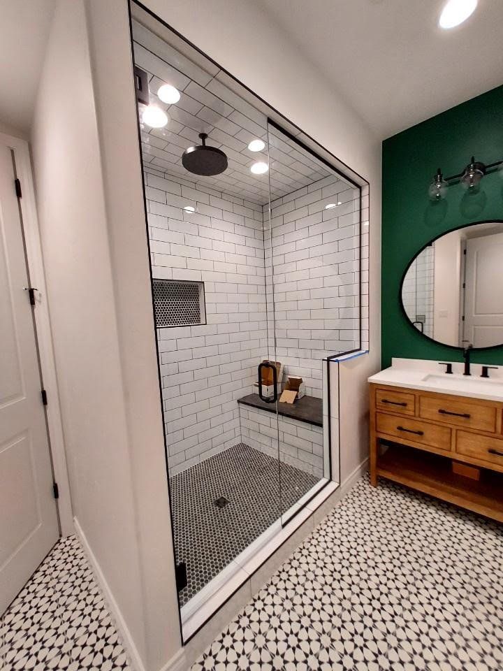 A bathroom with a walk in shower , sink and mirror.