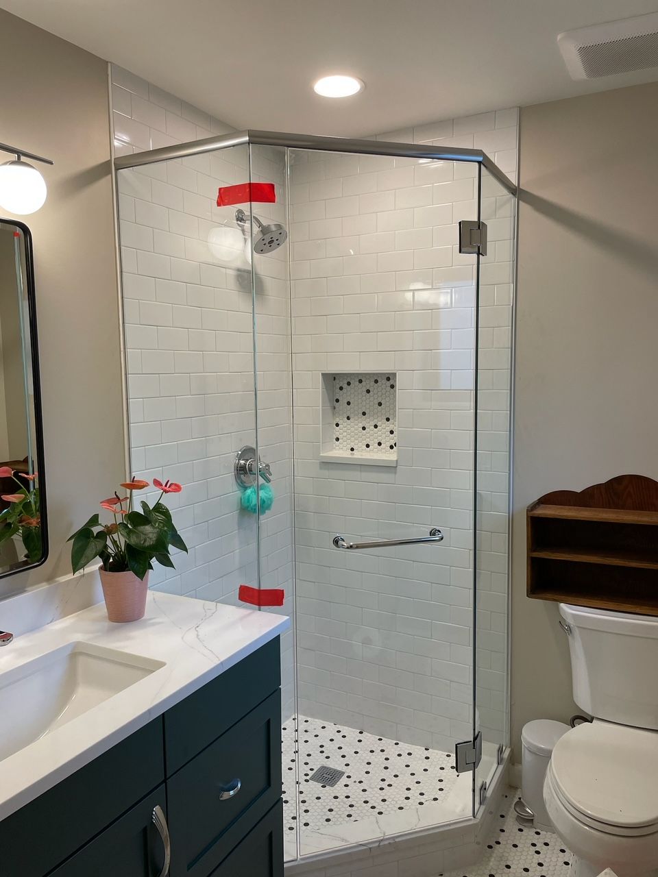 A bathroom with a walk in shower , sink , toilet and mirror.