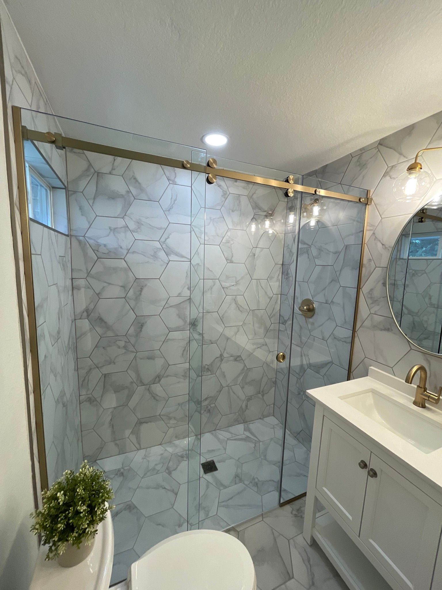 A bathroom with a walk in shower , toilet , sink and mirror.