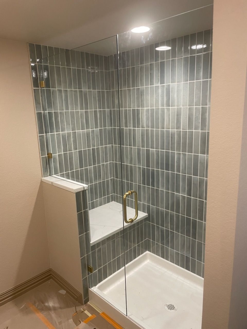 A bathroom with a walk in shower with a glass door.